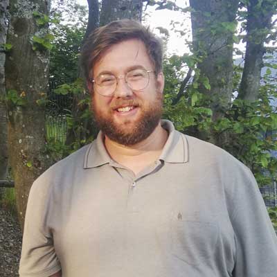Auf dem Bild ist das Vorstandsmitglied Andreas Heithe zu sehen. Er trägt eine Brille und lacht in die Kamera.