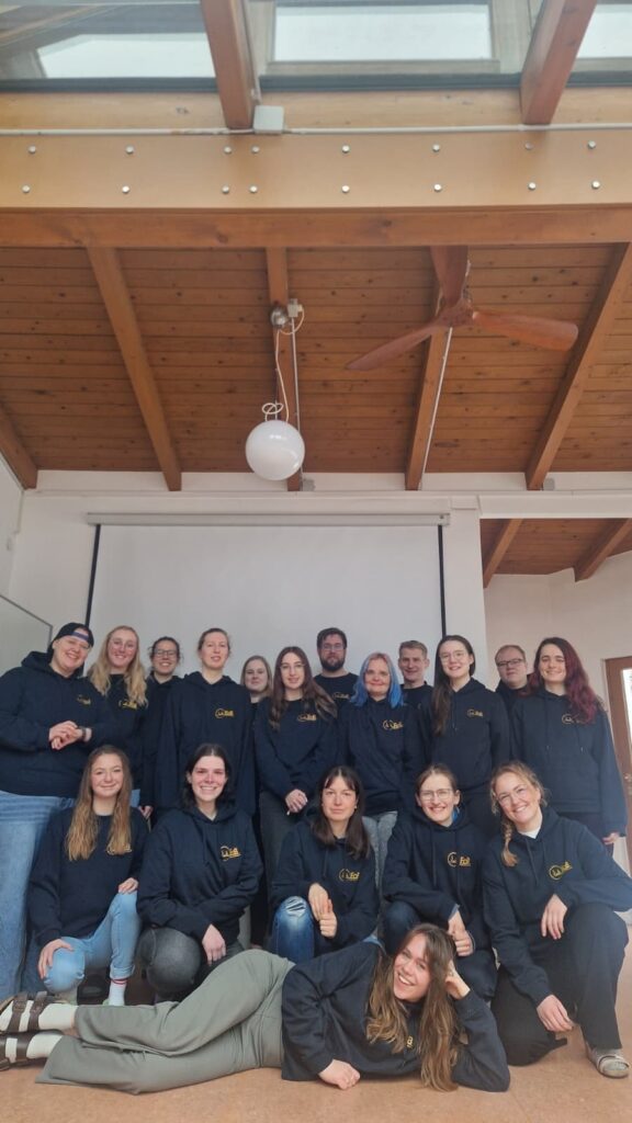 Gruppenfoto des Schulungsteams. Man sieht insgesamt 18 Personen. 12 Personen stehen hintern in einer Reihe, 5 hocken davor, 1 Mädchen liegt noch weiter davor. Alle gucken freundliche in die Kamera.
